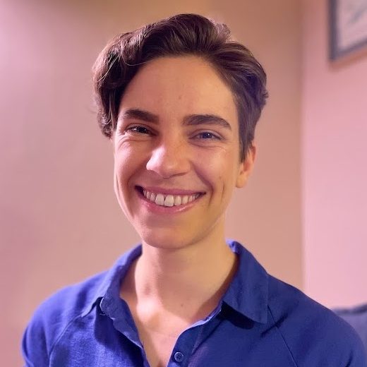 A picture of Adrian, a white non-binary person wearing a purple shirt