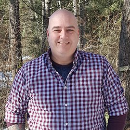 Photo of Jon, wearing a plaid red and white shirt.